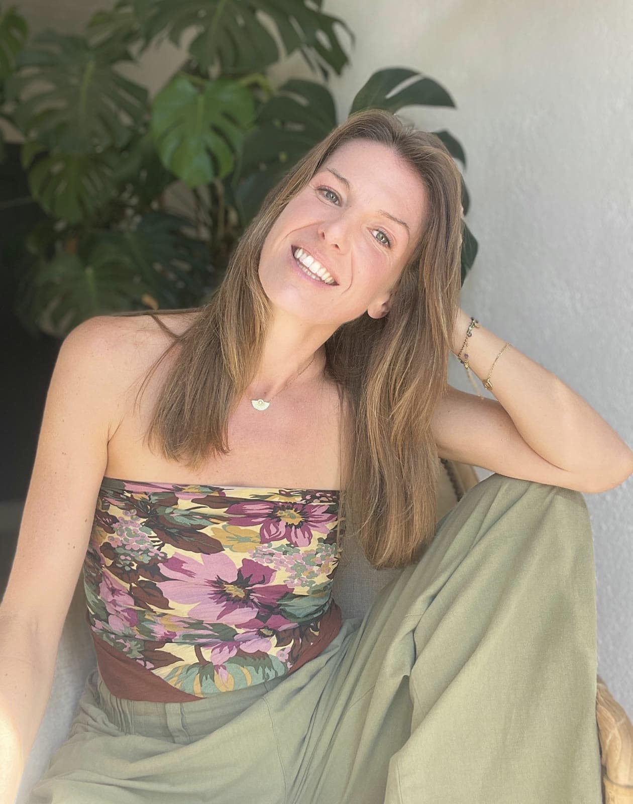 Morgane, souriante, assise devant une plante