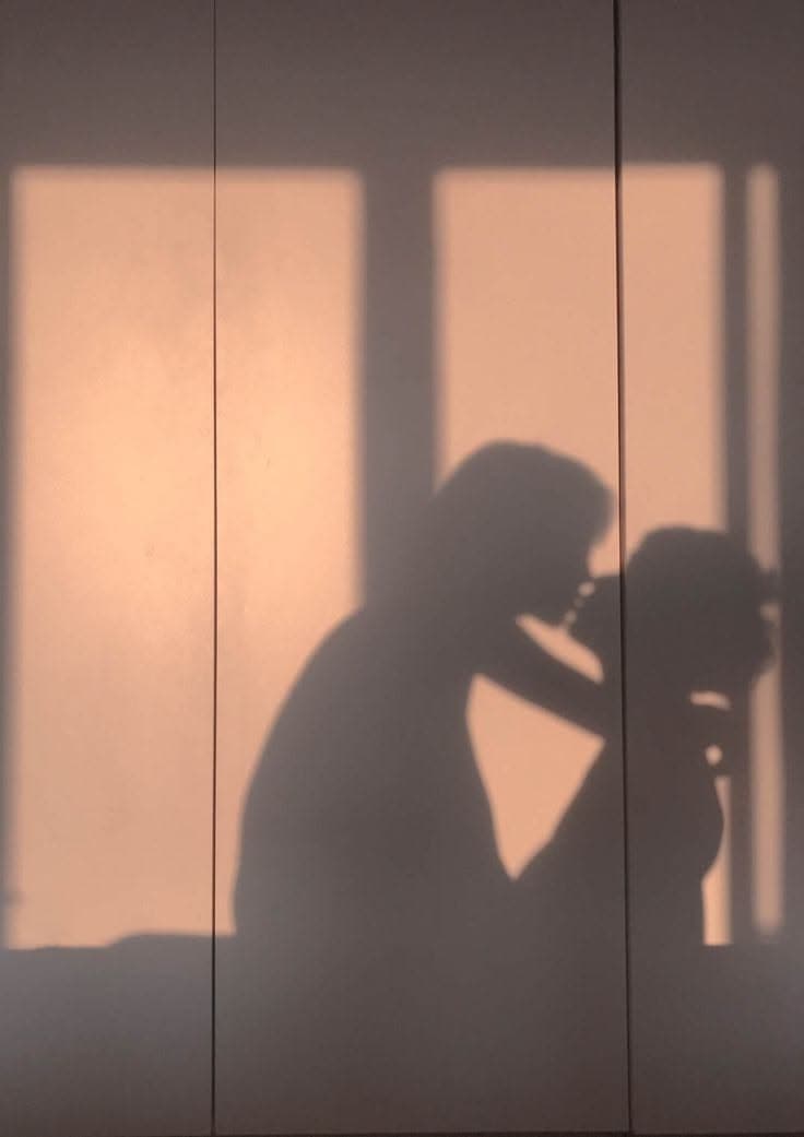Deux silhouettes en ombre sur un mur baigné de lumière chaude
