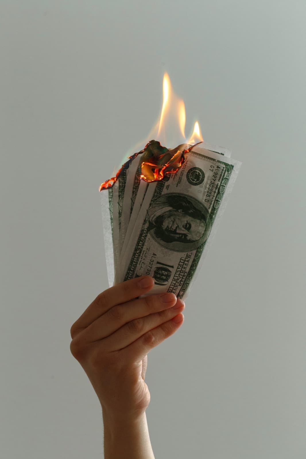 Une main tient des billets qui prennent feu